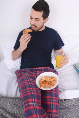 Adam yatakta kahvaltı yapıyor..