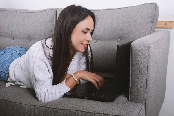 Жінка використовує ноутбук на дивані . — стокове фото