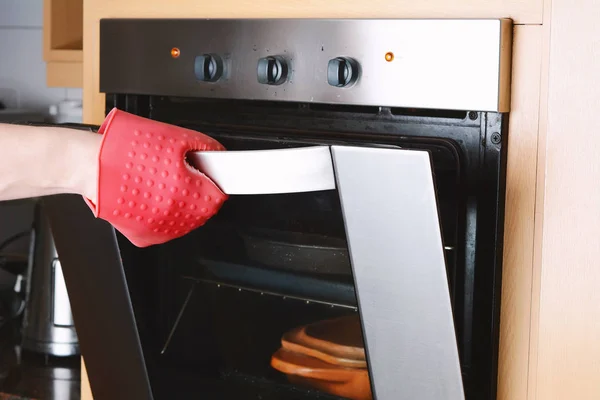 Виймання запеченого лотка з духовки з кухонними рукавичками — стокове фото