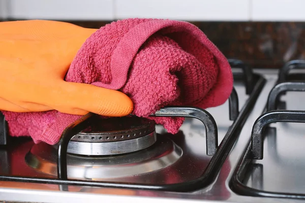 Stäng upp händerna i gummihandskar rengöring kokplattor — Stockfoto