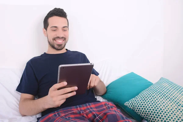 Hombre usando la tableta en la cama . — Foto de Stock