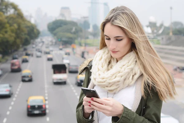 Ung kvinna skickar meddelanden med sin smartphone. — Stockfoto