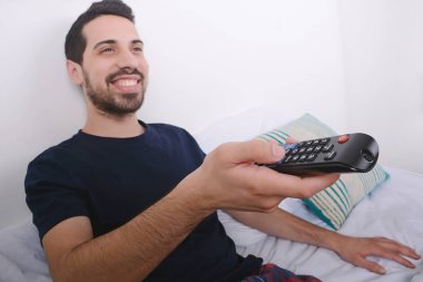 Adam yatakta TV izlerken.