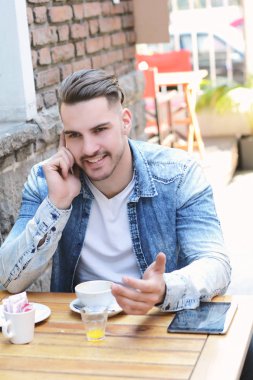 Telefonda konuşurken kafede genç adam. 