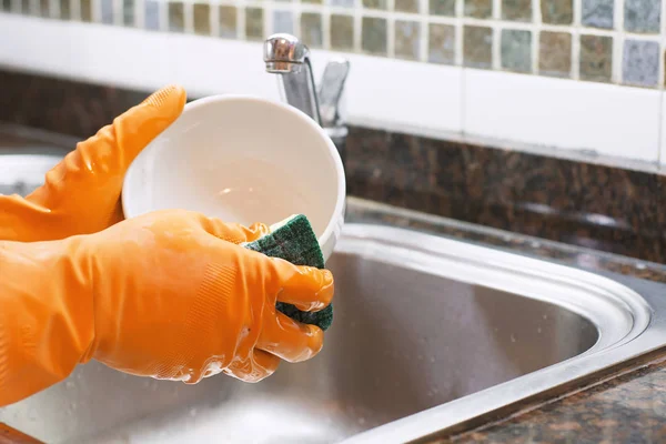 Mains dans les gants en caoutchouc laver la vaisselle avec du spon — Photo