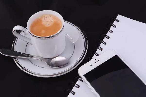 Uma xícara de café com um notepad e smartphone . — Fotografia de Stock