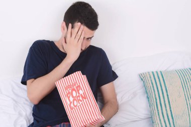 Patlamış mısır yemek ve film izlerken bir adam.