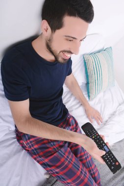 Adam yatakta TV izlerken.