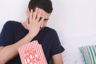 Patlamış mısır yemek ve film izlerken bir adam.