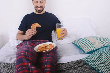 Adam yatakta kahvaltı yapıyor..