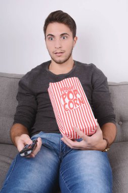 Patlamış mısır yemek ve film izlerken bir adam.