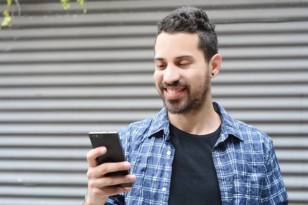 Latijnse man op zijn telefoon te typen. — Stockfoto