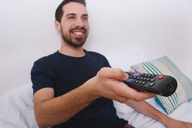 Adam yatakta TV izlerken.