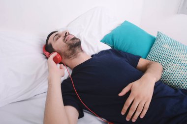 Adam yatakta müzik dinlemek.