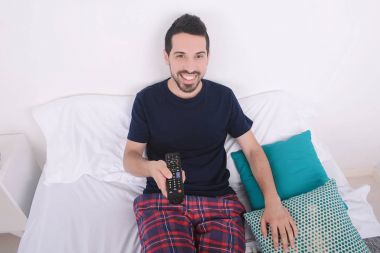 Adam yatakta TV izlerken.