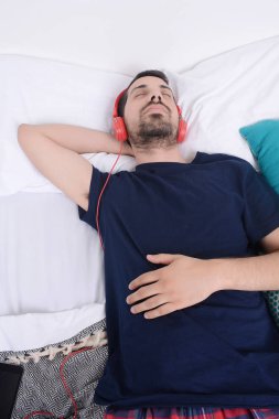 Adam yatakta müzik dinlemek.