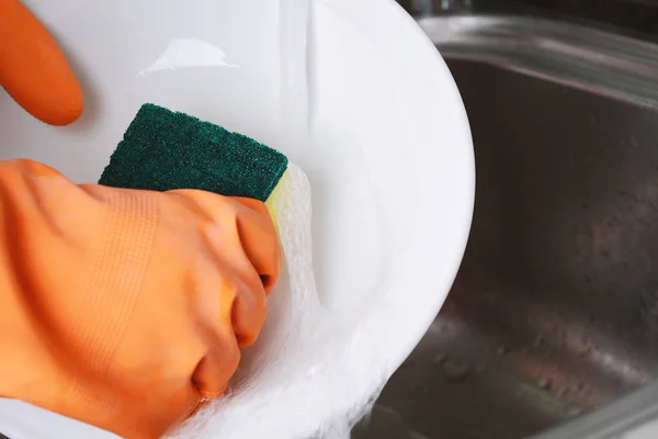 Hands in rubber gloves washing dishes with spon — Stock Photo, Image