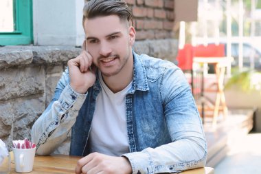 Telefonda konuşurken kafede genç adam. 