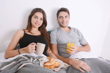 Çift yatakta kahvaltı yapıyor..