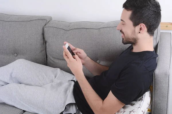 Kanepeye Smartphone kullanan adam.