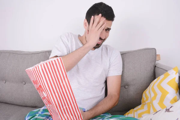 Patlamış mısır yemek ve film izlerken bir adam.