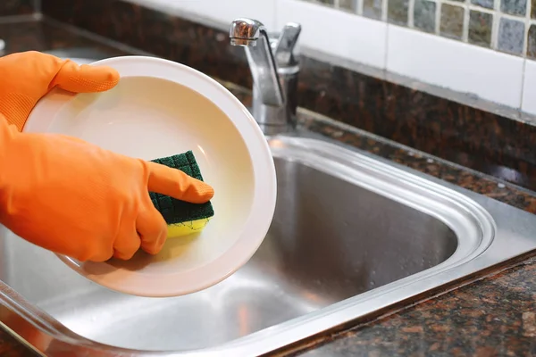 Manos en guantes de goma lavando platos con spon — Foto de Stock