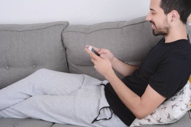 Kanepeye Smartphone kullanan adam.