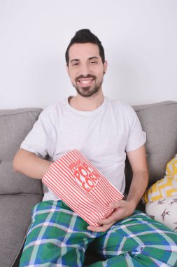 Patlamış mısır yemek ve film izlerken bir adam.