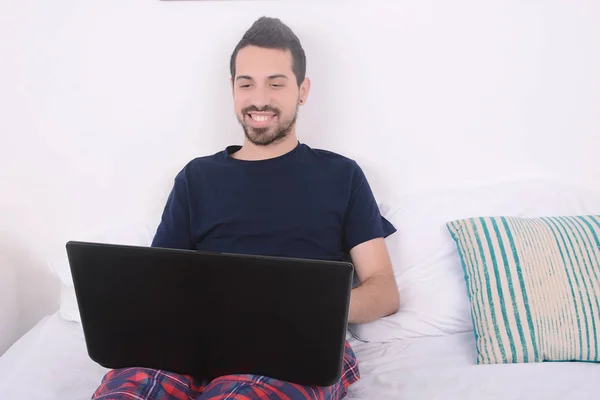Hombre usando el ordenador portátil en la cama . — Foto de Stock