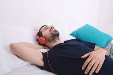 Adam yatakta müzik dinlemek.