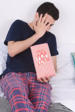 Patlamış mısır yemek ve film izlerken bir adam.