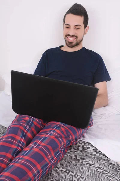 Homme utilisant un ordinateur portable au lit . — Photo