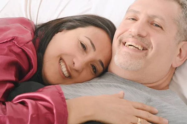 Middle-age couple relaxing together on their bed — Stock Photo, Image