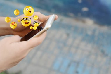 Woman using smartphone sending emojis. clipart