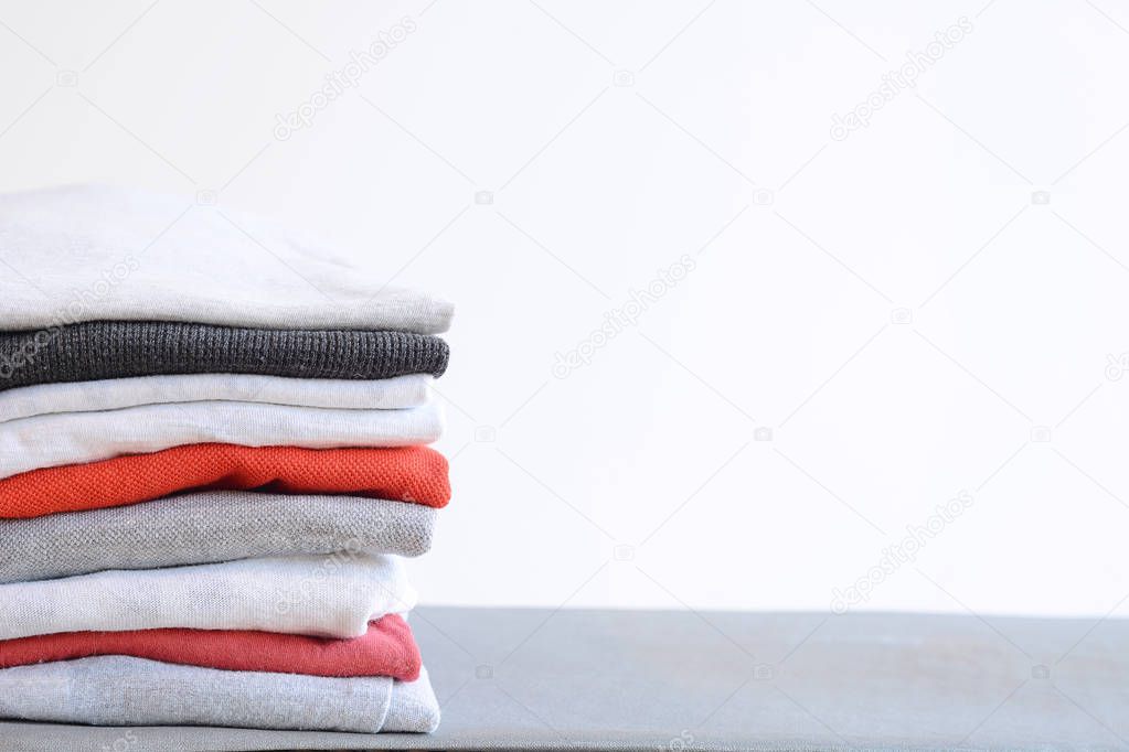 Stack of colorful folded shirts on gray table 