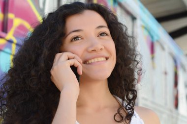 Genç bir kadın cep telefonuyla konuşuyor..