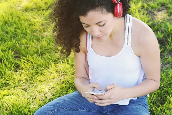 Mujer latina joven con auriculares en un parque . —  Fotos de Stock