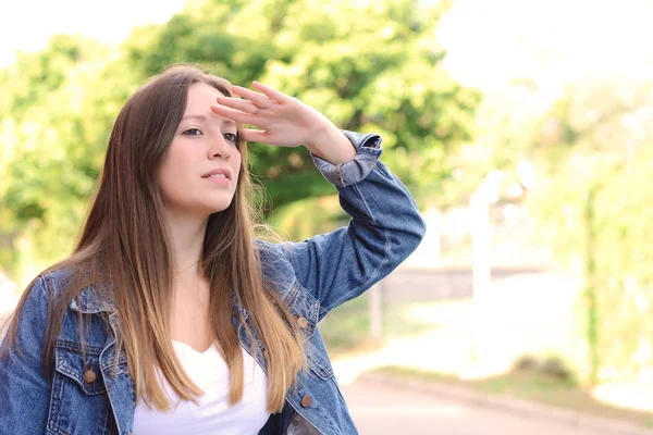 Junge Frau blickt weit mit der Hand auf ihre Stirn. — Stockfoto