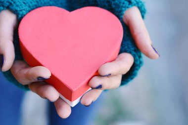 Kalp tutan eller hediye kutusu şeklinde.