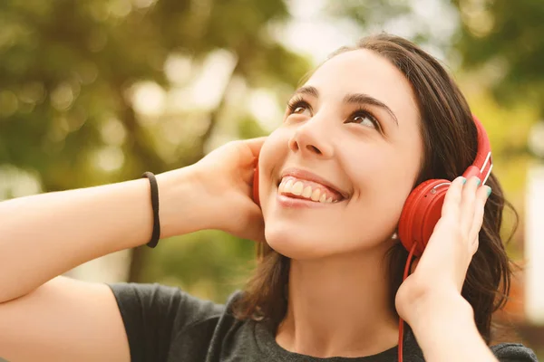 Portret van jonge mooie vrouw met rode hoofdtelefoon luisteren — Stockfoto