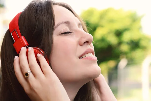 Mujer latina joven con auriculares en un parque . — Foto de Stock