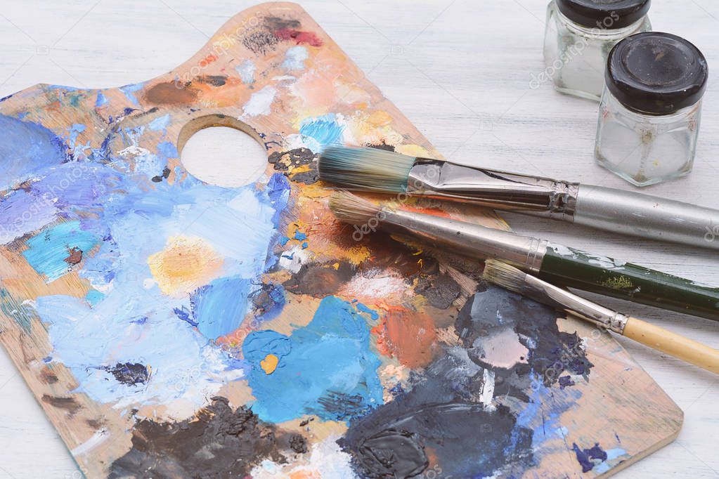 Artist's palette with colorful oil paint strokes and paintbrushe