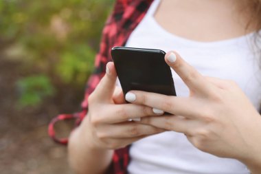 Akıllı telefon kullanan genç bir kadın.