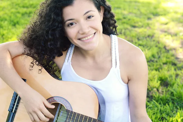 Mujer joven tocando la guitarra en el parque . — Foto de Stock