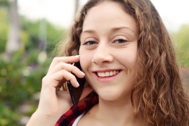 Genç bir kadın cep telefonuyla konuşuyor..