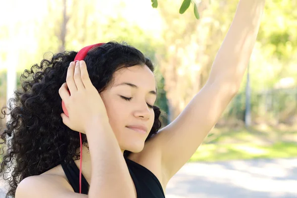 Mladá Latina žena se sluchátky v parku. — Stock fotografie