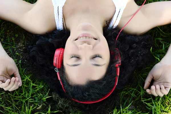 Mladá Latina žena se sluchátky v parku. — Stock fotografie