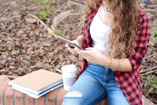 Молодой студент в парке с планшетом, кофе и книгами . — стоковое фото