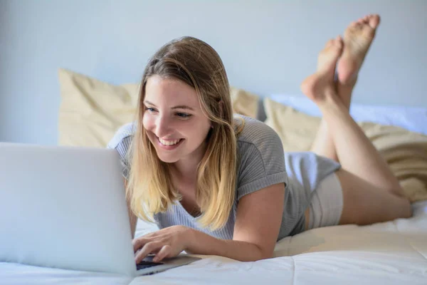 Молода жінка використовує свій ноутбук на ліжку — стокове фото