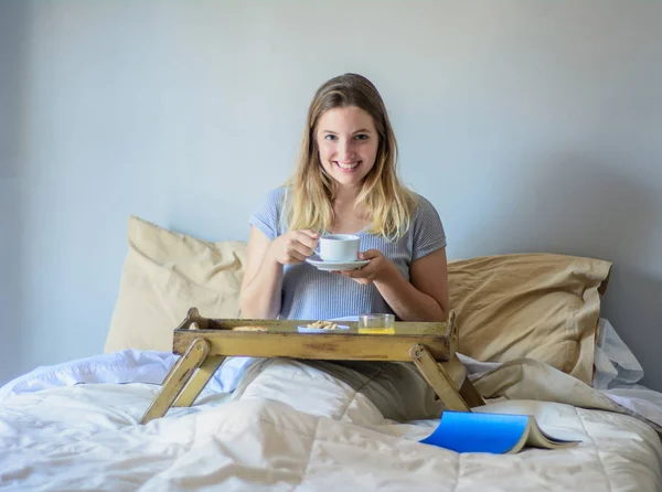 Jovem mulher tomando café da manhã na cama — Fotografia de Stock